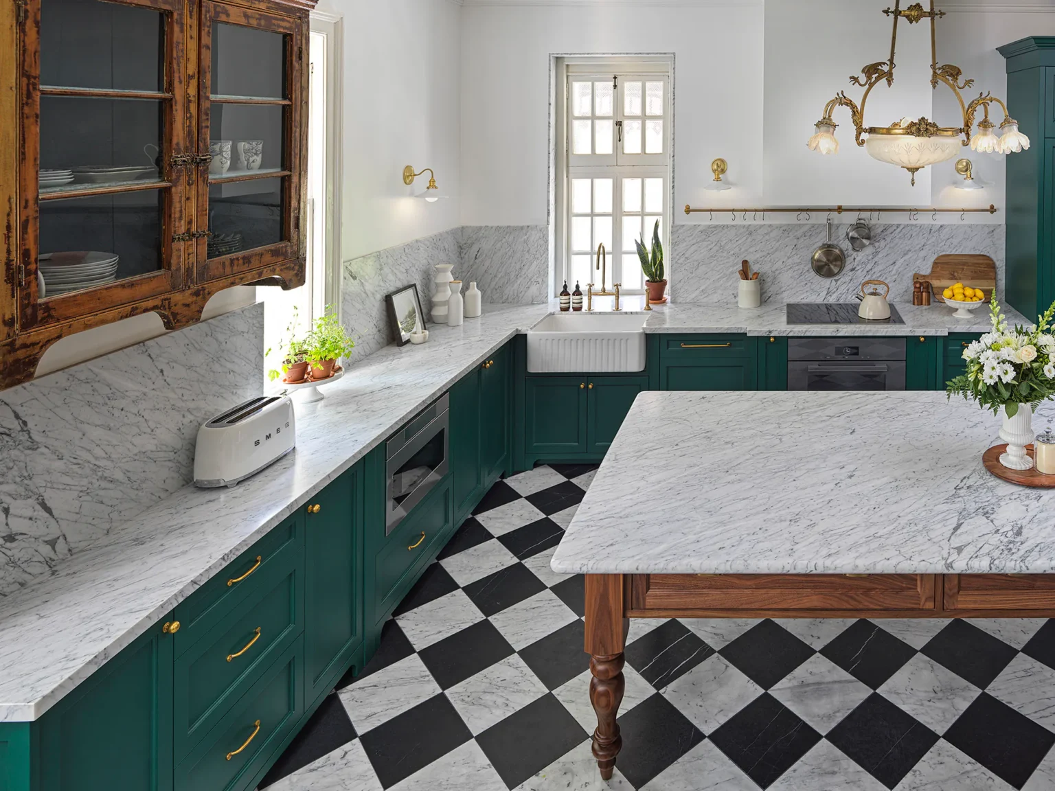 Marble-topped walnut island in front of green perimeter cabinetry