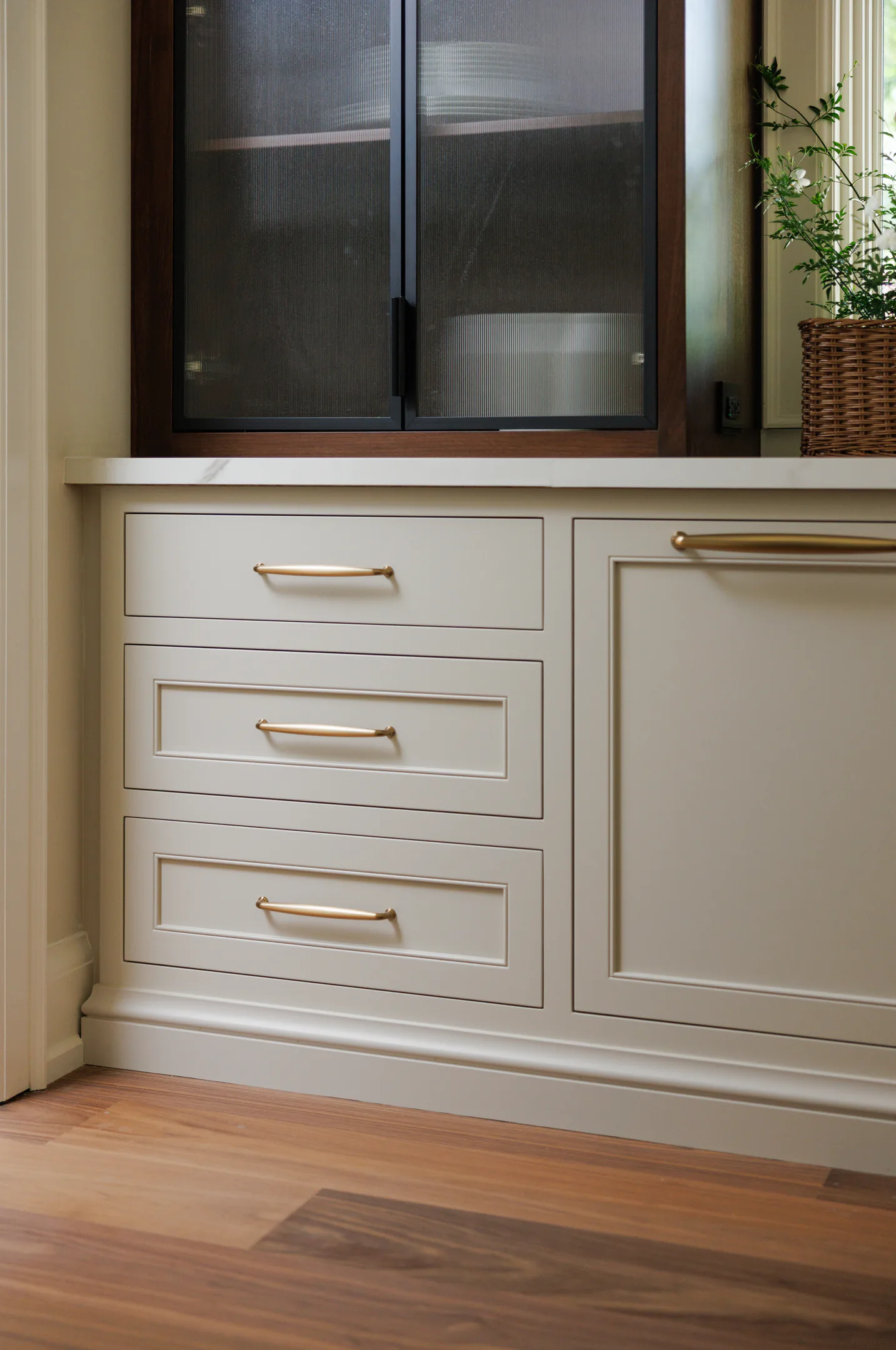 Painted cabinetry with a dark glass upper cabinet