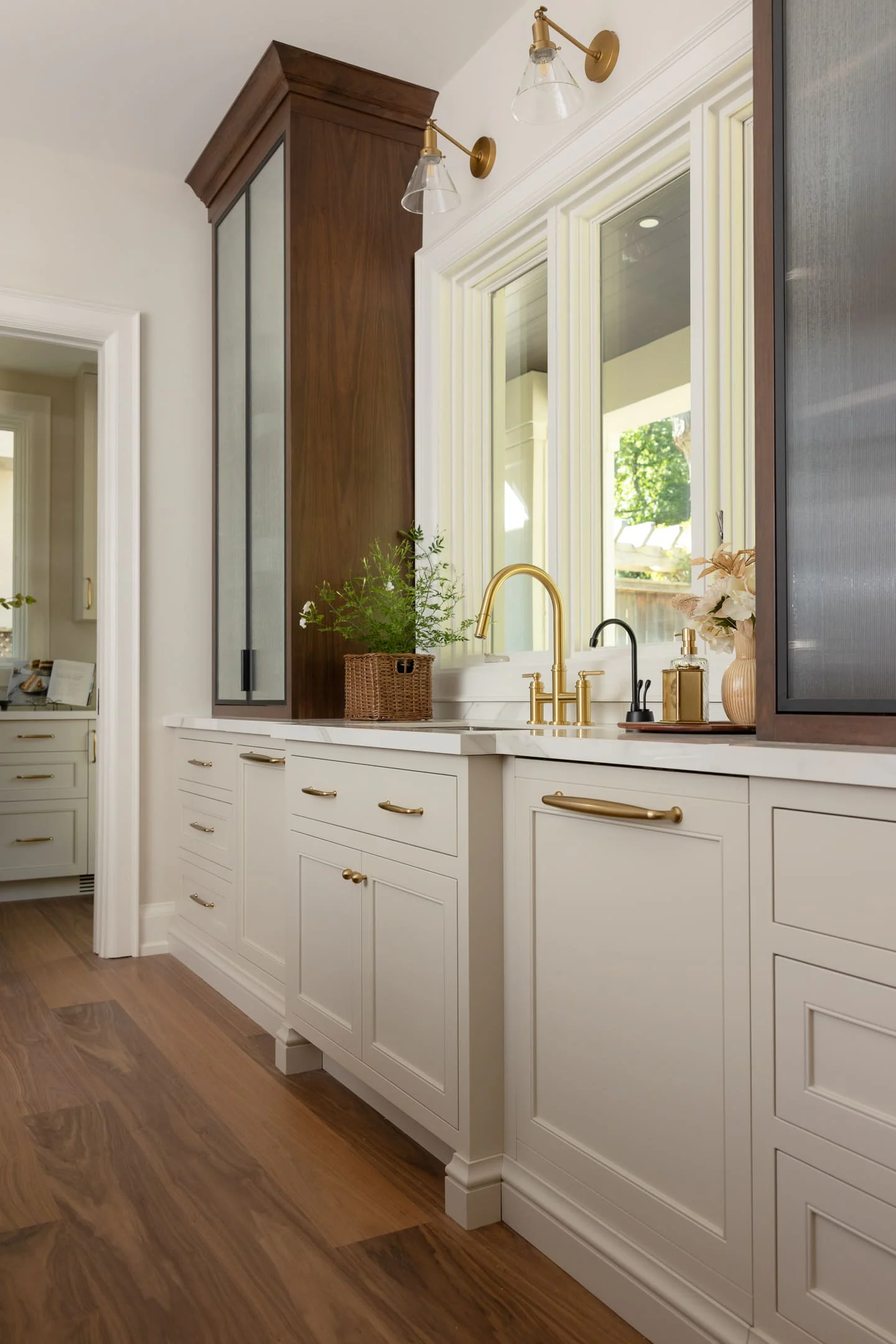 Tall walnut hutch with reeded glass doors beside the sink wall