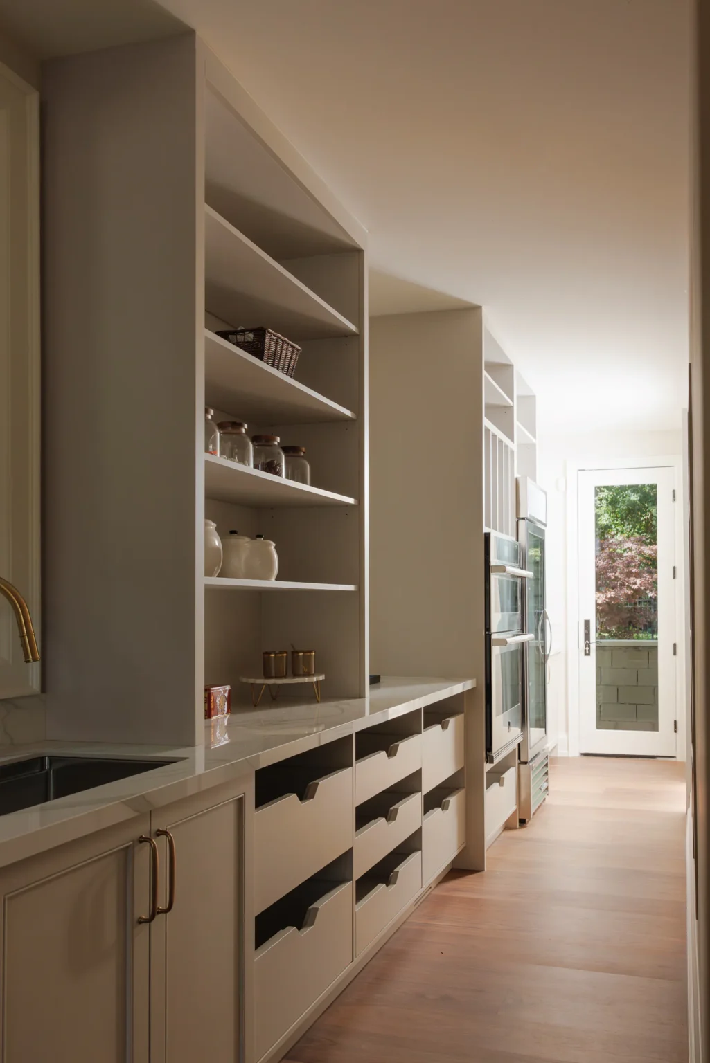 Pantry with painted cabinetry and open shelving