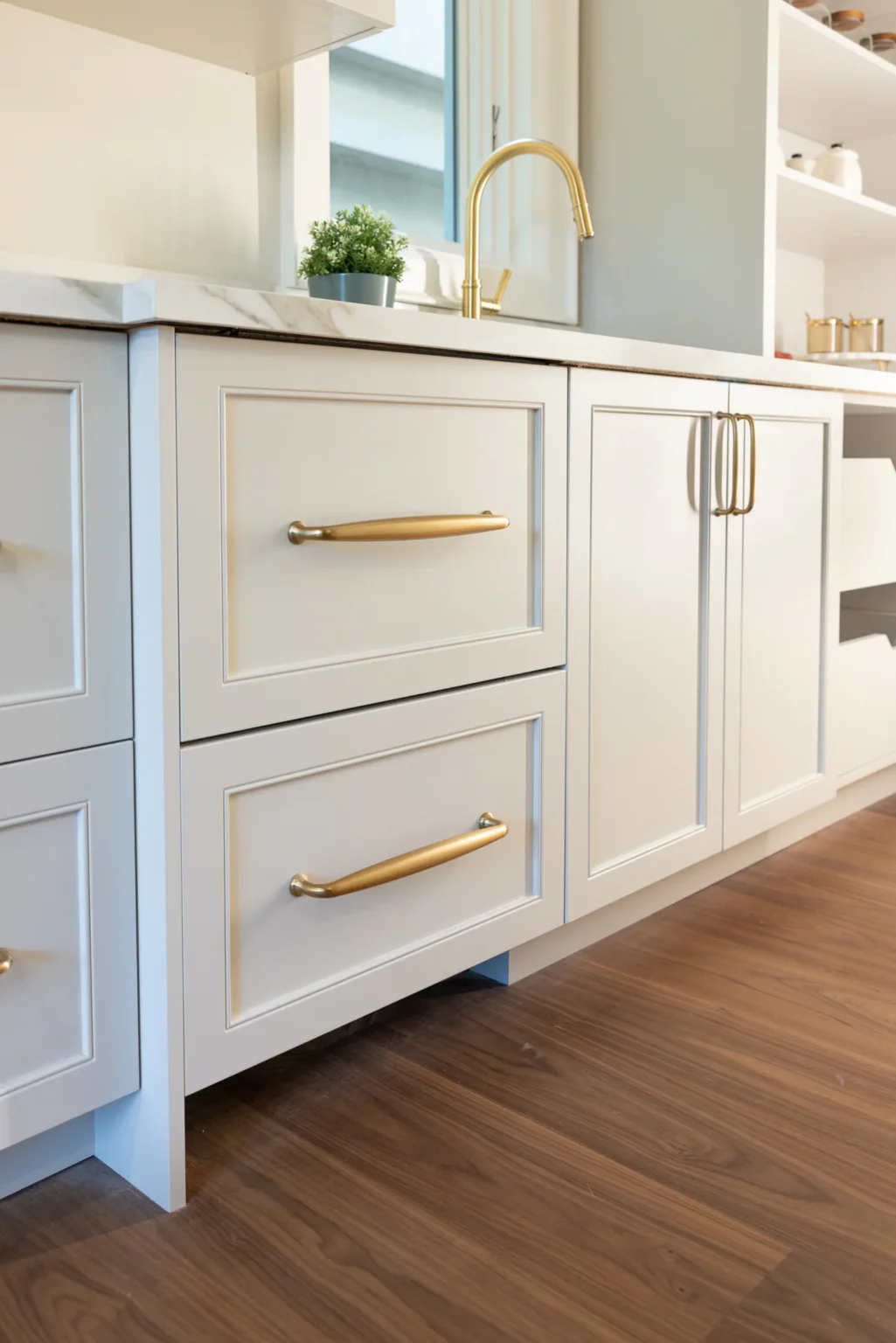 Painted lower cabinetry with brass hardware and a furniture-style toe kick