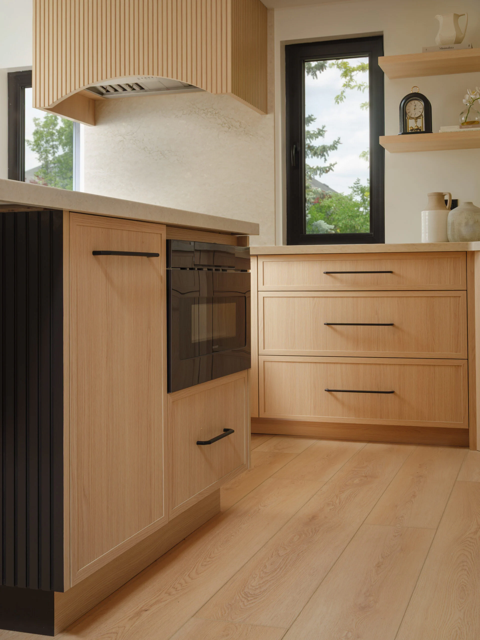 Custom range hood with an arched base, open shelving and island cabinetry in an Oakville kitchen