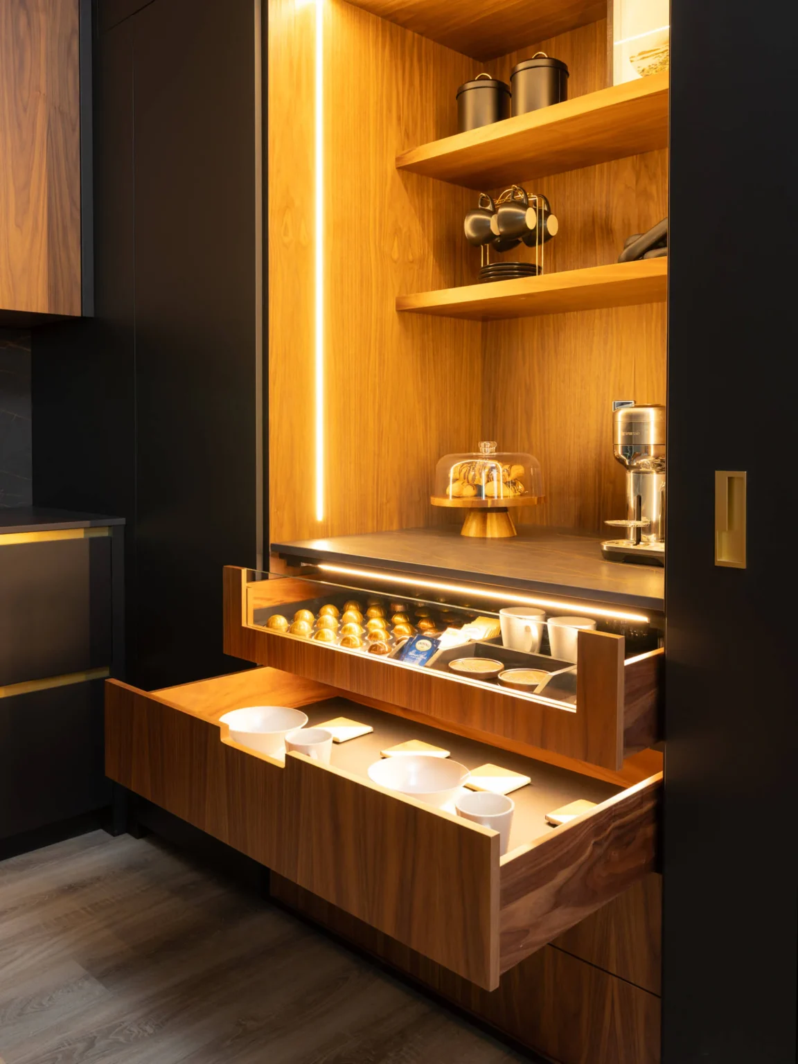 Open coffee bar with lit walnut shelving and a custom drawer insert