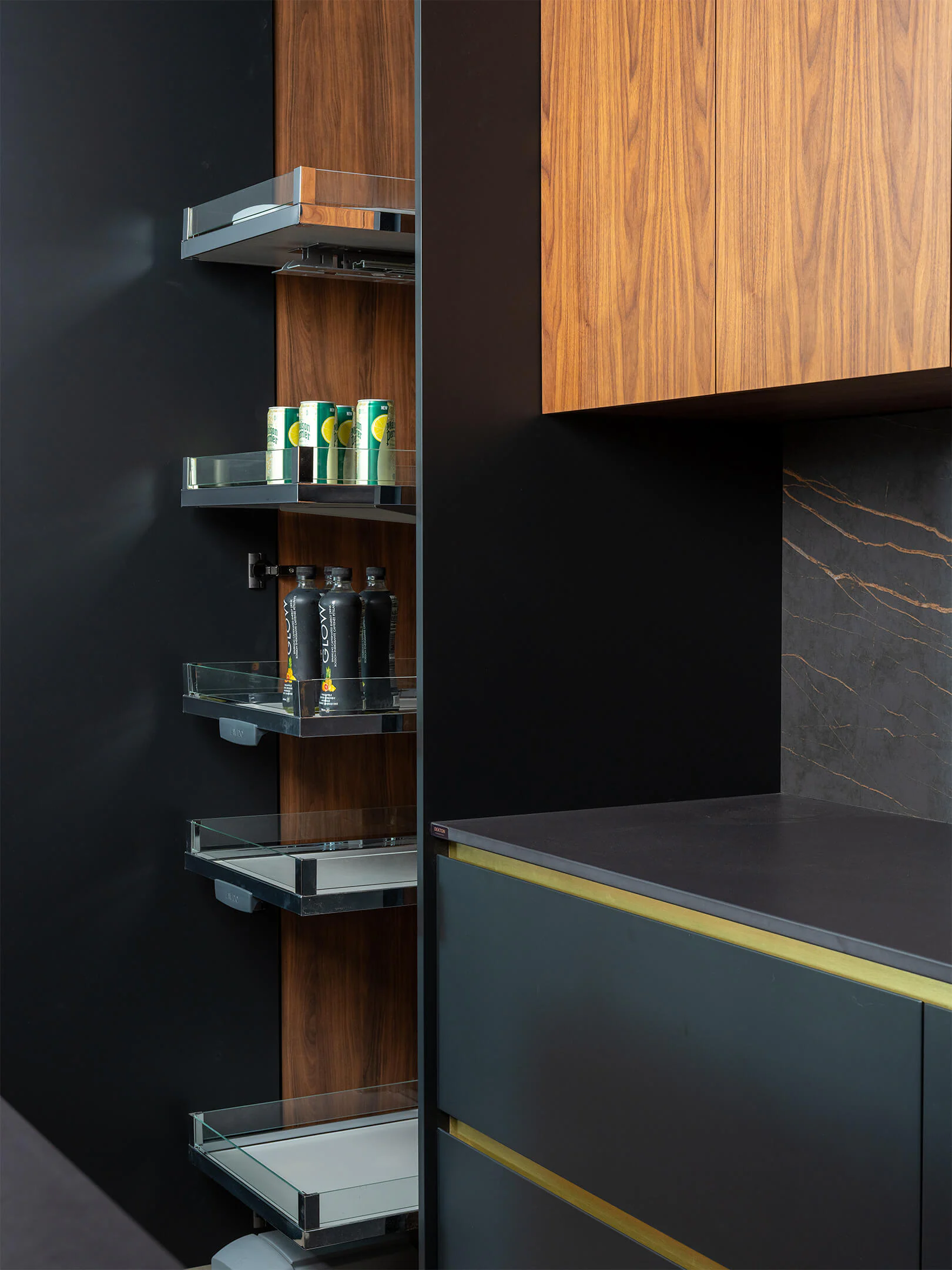 Tall pull-out pantry with metal shelving beside walnut and black cabinetry