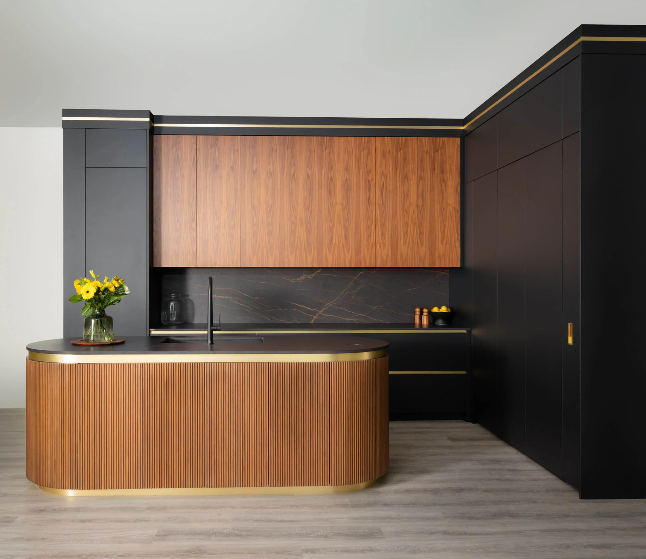 Contemporary kitchen with matte-black cabinetry and a curved, hand-reeded walnut island