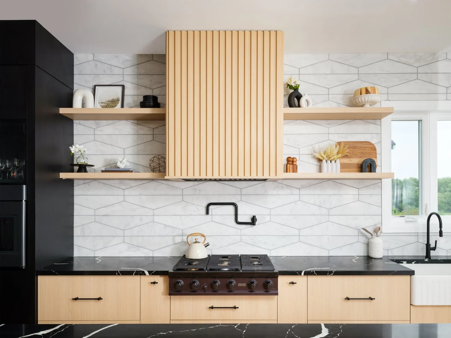 Reeded wood range hood with long floating shelves above a black stone countertop
