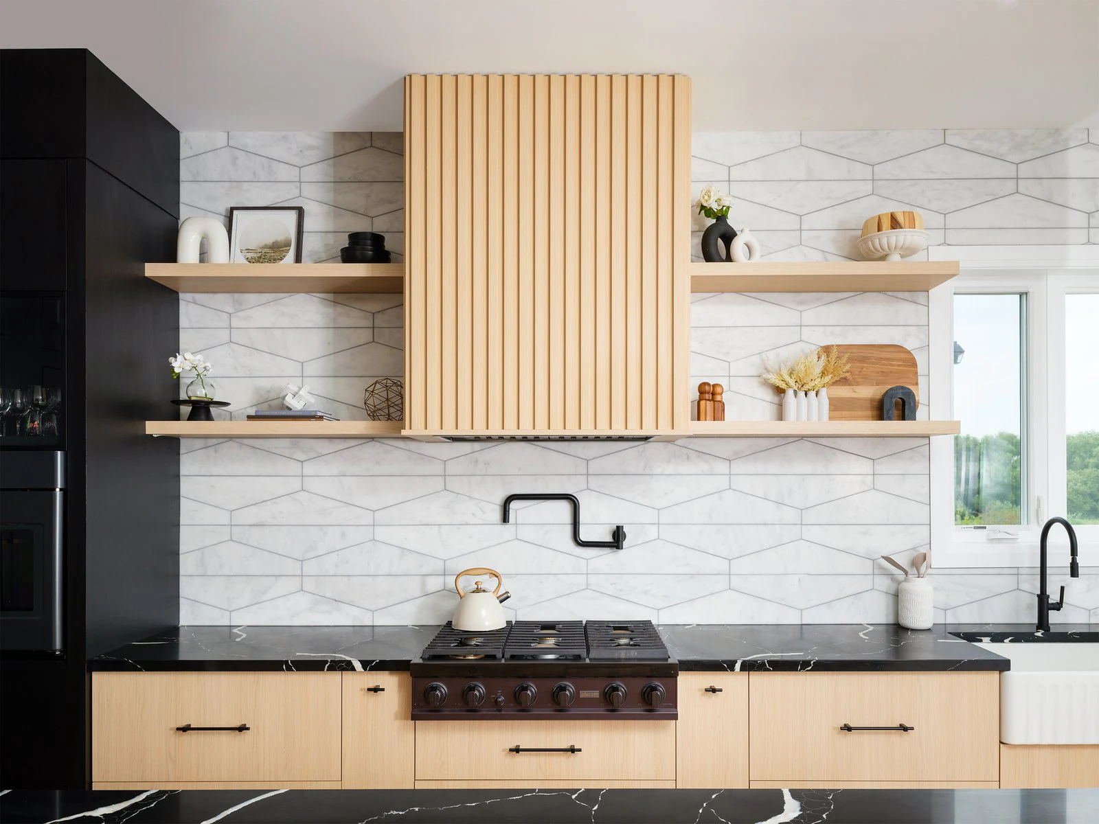 Reeded wood range hood with long floating shelves above a black stone countertop