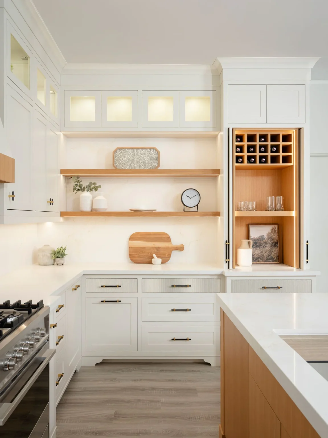Painted cabinetry with lit glass-front upper cabinets, open wood shelving and a built-in wine rack