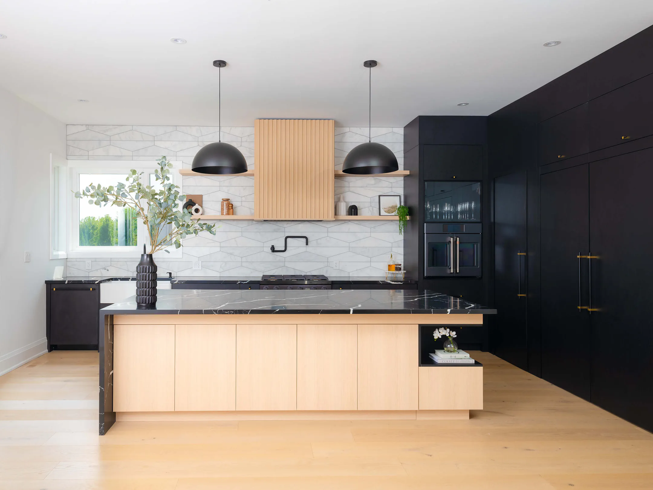 Wide view of the kitchen with dark cabinetry, the island and pendant lighting