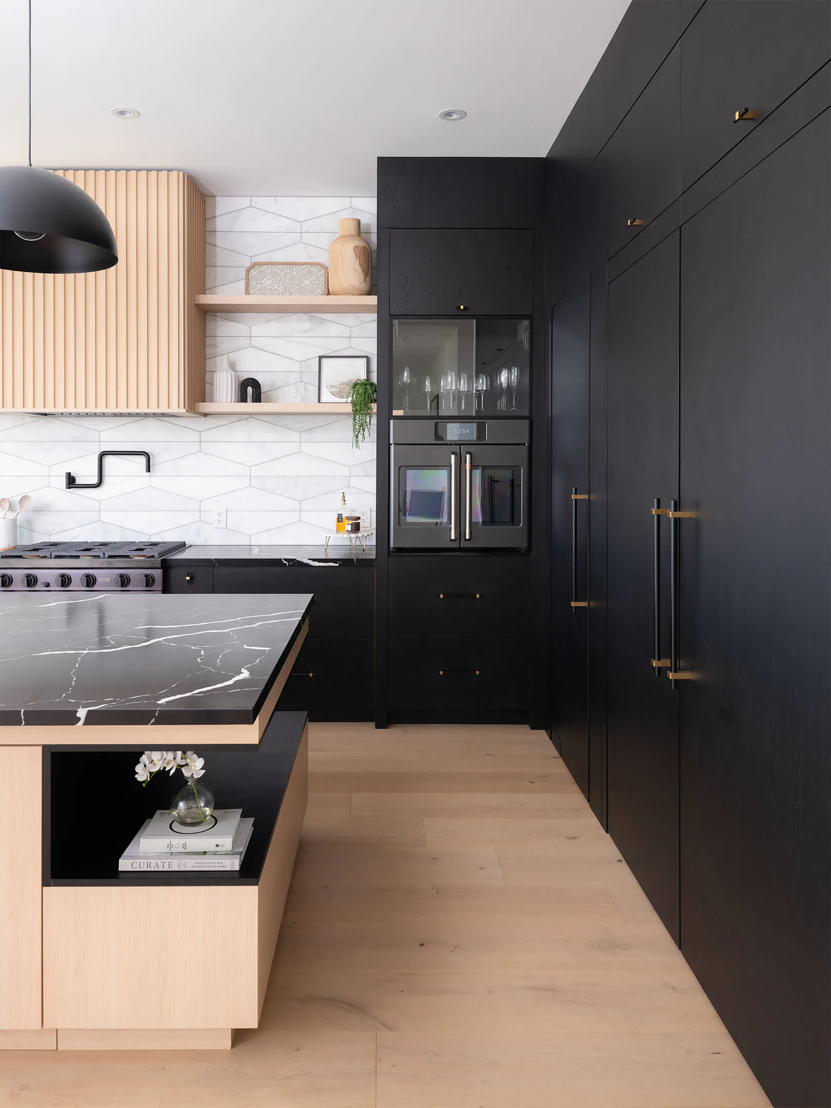 Island and dark full-height cabinetry seen from the end of the kitchen