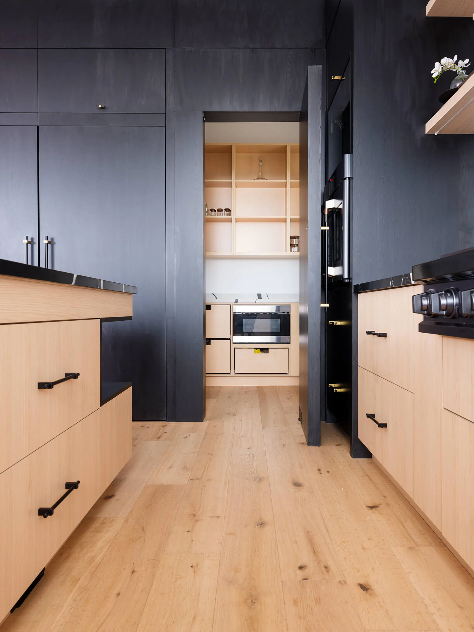 Pantry entrance set into the dark wall panelling, opening into a lighter wood pantry