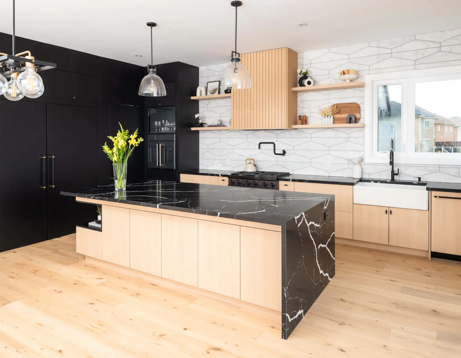 Modern kitchen with dark full-height cabinetry, light wood cabinetry and a black stone waterfall island