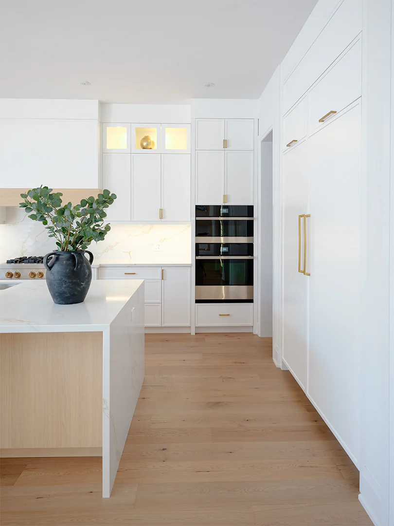 White oak island with a stone waterfall end and painted cabinetry behind