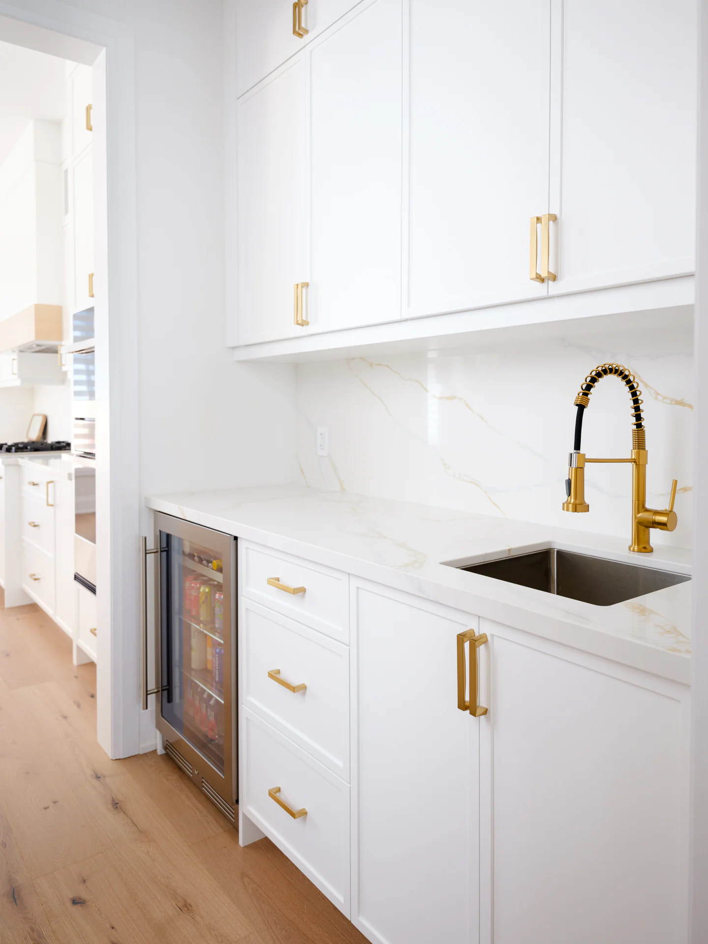 Servery with painted cabinetry, a beverage fridge and brass hardware