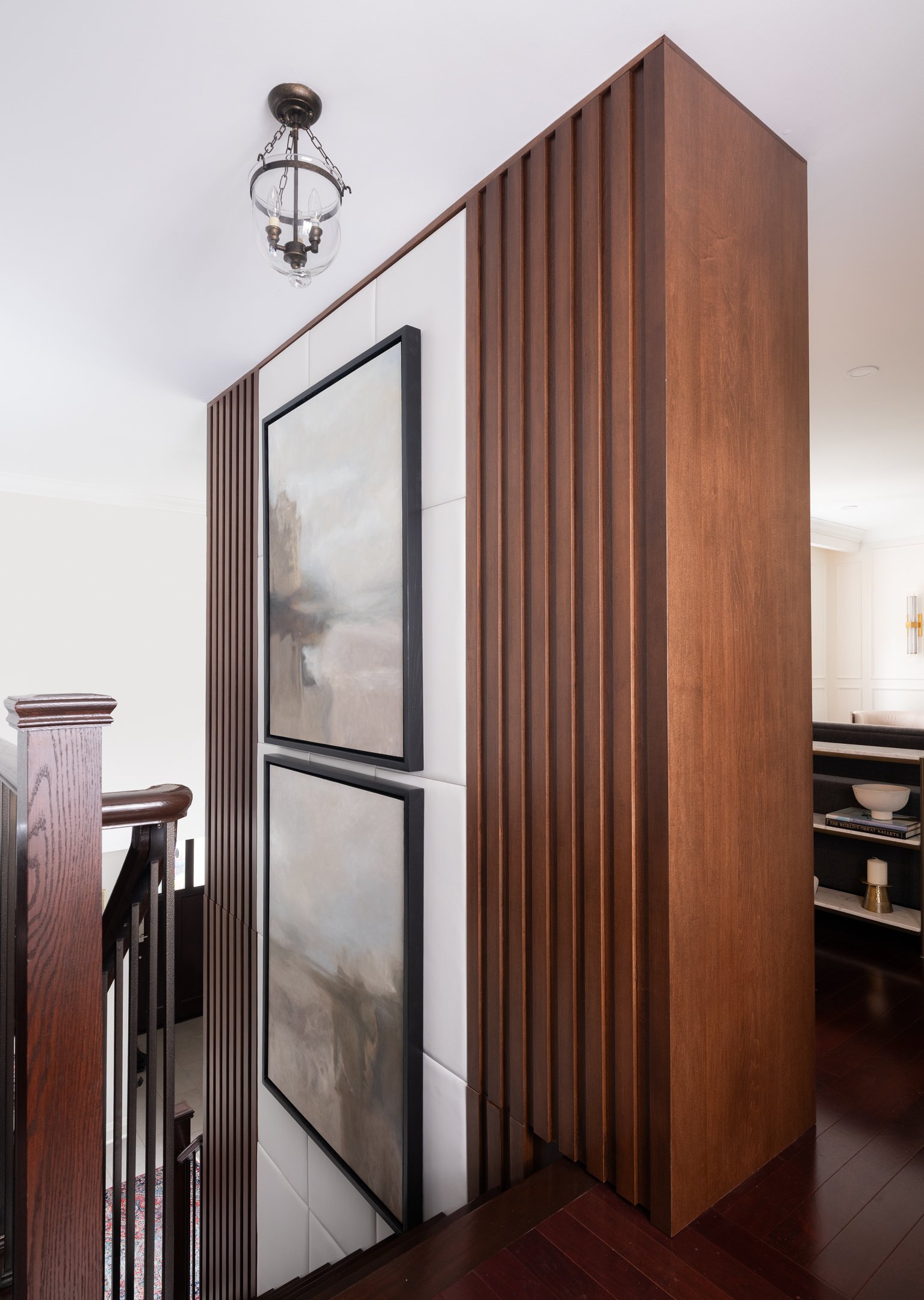 Custom wood slat feature wall with framed artwork beside a staircase
