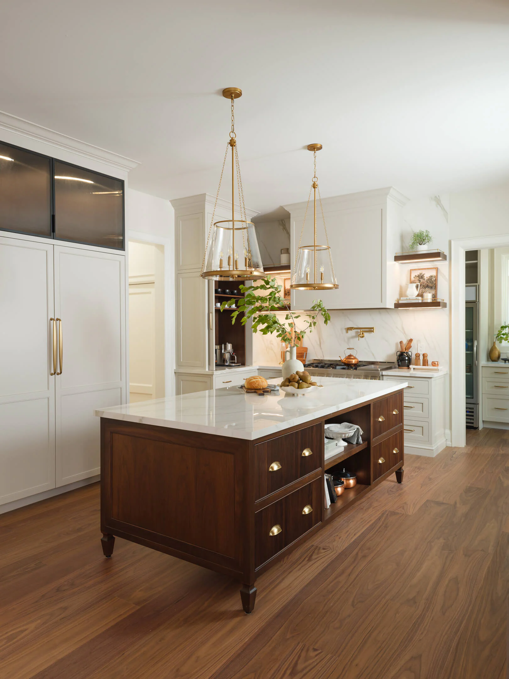 Furniture-style walnut island with drawers and open shelving under pendant lights